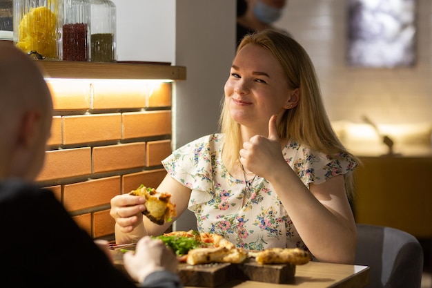 Foto junges paar, das pizza genießt, während es in der pizzeria sitzt