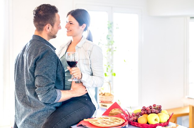 Junges Paar, das Rotwein im zarten Moment zu Hause Küche röstet