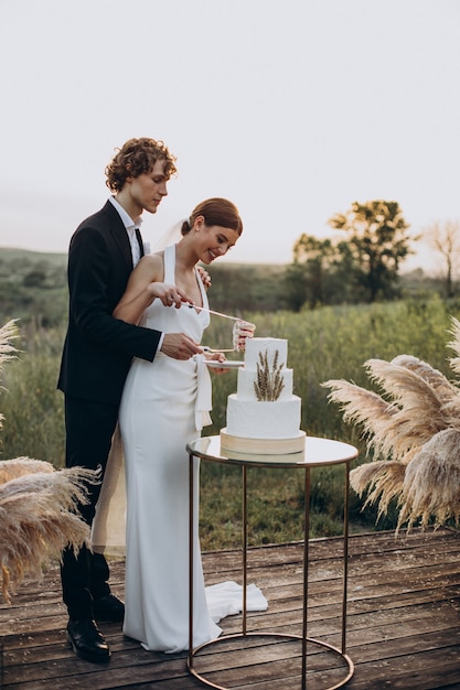 Junges Paar, das seine Hochzeitstorte anschneidet