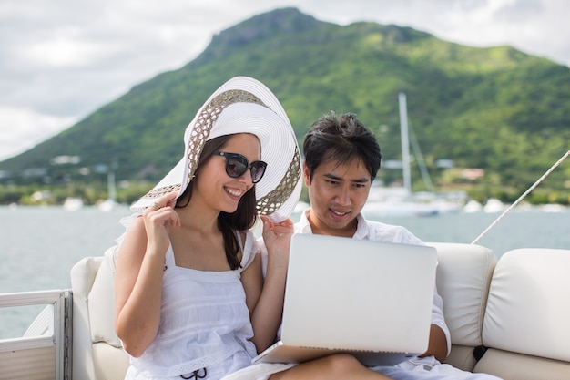 Junges Paar, das Spaß auf dem Boot mit einem Laptop hat