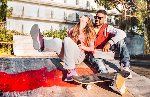 Junges Paar, das Spaß zusammen am Skatepark mit Musikboombox hat