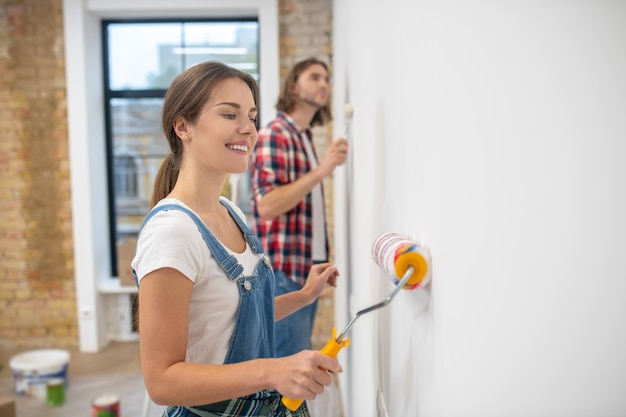 Junges Paar, das Wand in ihrem neuen Haus malt