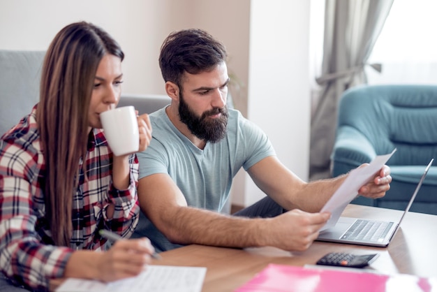 Junges Paar, das zu Hause Familienfinanzen erledigt