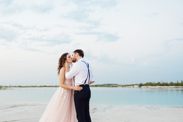 Junges Paar, ein Mann in schwarzen Reithosen und ein Mädchen in einem rosa Kleid, gehen durch den weißen Sand der Wüste