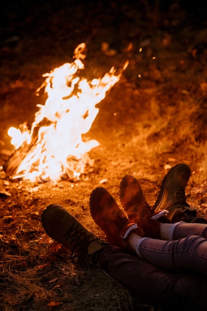 Junges Paar, ein Mann und ein Mädchen in hellen Strickmützen, hielten auf einem Campingplatz in der Nähe des Feuers an