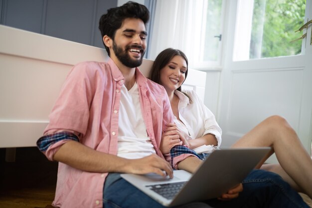 Junges Paar entspannt auf dem Bett mit Laptop. Liebe, Technologie, Glück, Menschen und Spaßkonzept.