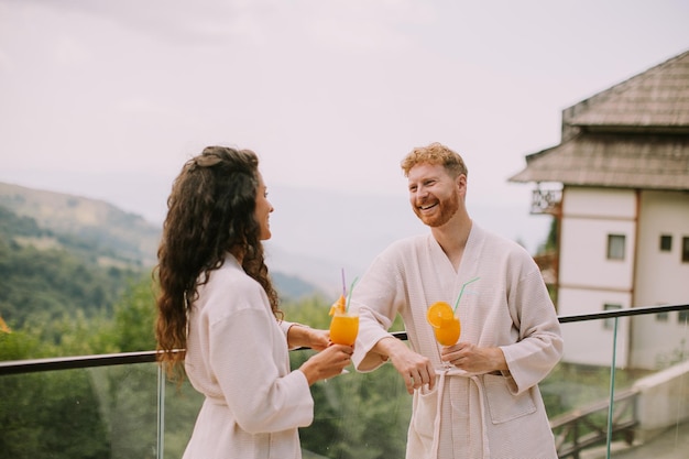 Junges Paar entspannt sich auf der Außenterrasse und trinkt frischen Orangensaft