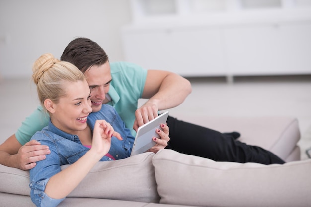 Junges Paar Entspannung im luxuriösen Haus mit Tablet-Computer lesen im Wohnzimmer auf der Sofa-Couch.