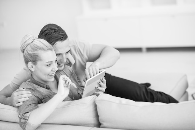 Junges Paar Entspannung im luxuriösen Haus mit Tablet-Computer lesen im Wohnzimmer auf der Sofa-Couch.