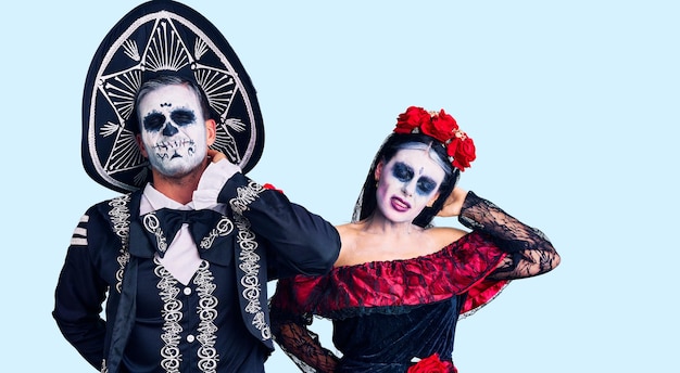Junges Paar im mexikanischen Tag der Toten-Kostüm über dem Hintergrund, das an Nackenschmerzen leidet, den Hals mit der Hand berührt, Muskelschmerzen
