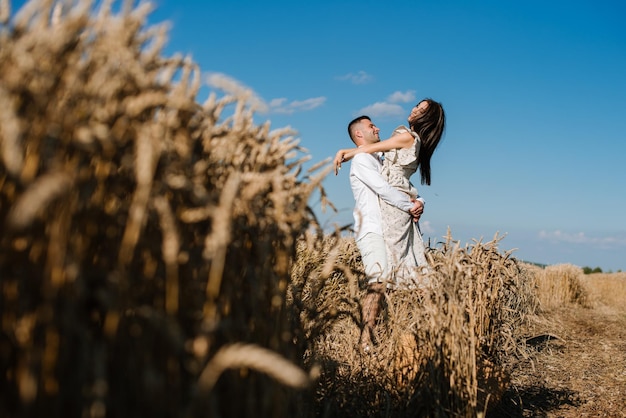 Junges Paar im Weizenfeld an einem sonnigen Sommertag. Verliebte Paare haben Spaß im goldenen Feld. Romantisches Paar in Freizeitkleidung im Freien auf grenzenlosem Feld