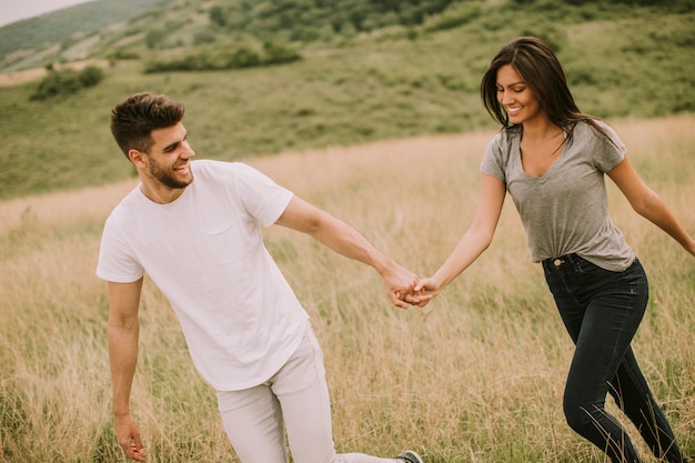 Junges Paar in der Liebe, die durch Grasfeld geht