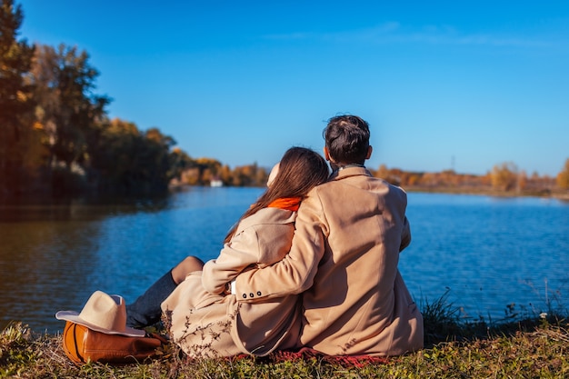 Junges Paar in der Liebe, die durch Herbstsee kühlt. Glücklicher Mann und Frau, die Natur genießen und umarmen. Im Freien entspannen