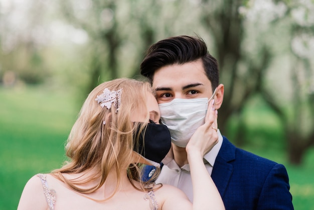 Junges Paar in medizinischen Masken im Park