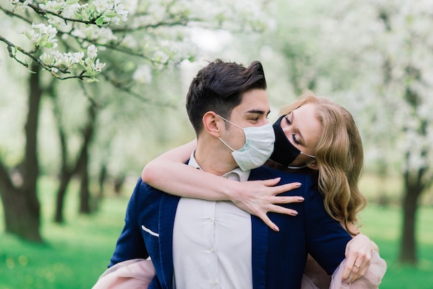 Junges Paar in medizinischen Masken im Park