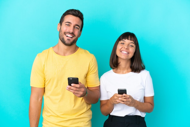 Junges Paar isoliert auf blauem Hintergrund mit Handy
