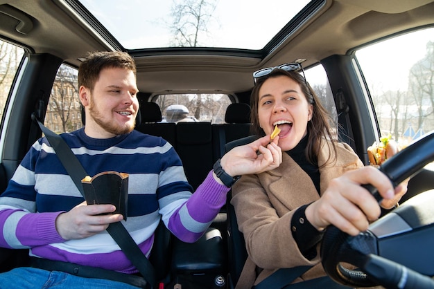 Junges Paar isst Fastfood im Auto