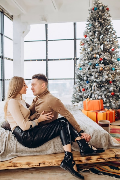 Junges Paar kuschelt neben Weihnachtsbaum zu Hause