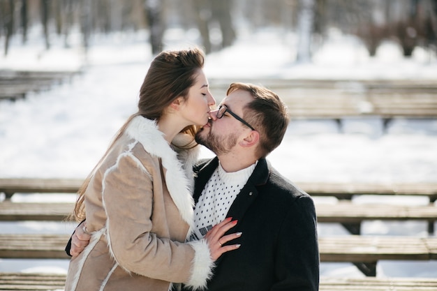 Junges Paar lächeln und küssen im Park im Winter