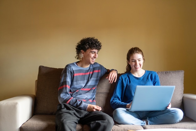 Junges Paar lächelt, während es seinen Laptop für die Freizeit benutzt