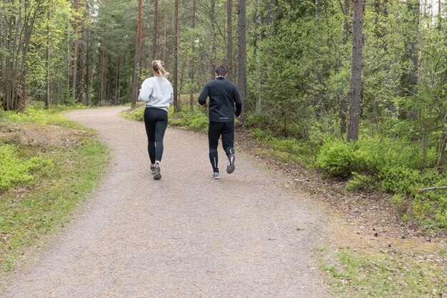 Foto junges paar läuft in einem wald. mann und frau joggen in der natur