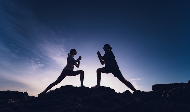 Junges Paar macht Yoga-Übungen am Bergrand bei Sonnenaufgang