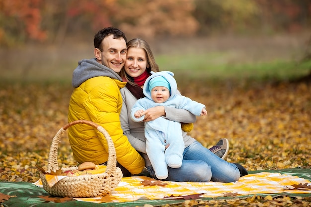 Foto junges paar mit baby auf picknick im herbstpark