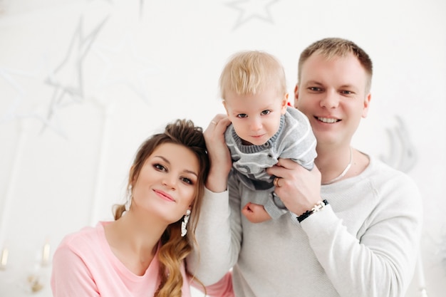 Foto junges paar mit dem kleinen sohn, der im weihnachtsstudio steht, vorne schaut und aufwirft