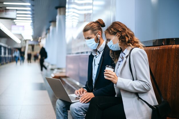 Junges Paar mit einem Laptop auf dem U-Bahnsteig