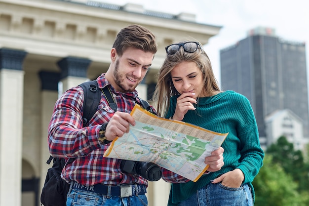 Junges Paar mit einer Karte in der Stadt. Besichtigungsstadt der glücklichen Touristen mit Karte