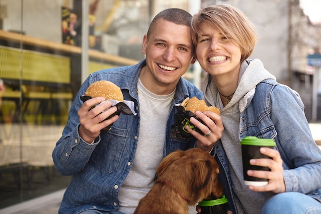 Junges Paar mit Hund, der Fast-Food-Mittagessen hat