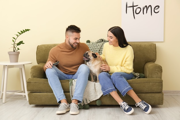 Junges Paar mit Hund, der Fernsehen beim Sitzen auf Sofa zu Hause sieht