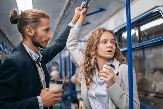 junges Paar mit Kaffee zum Mitnehmen in einem U-Bahnwagen