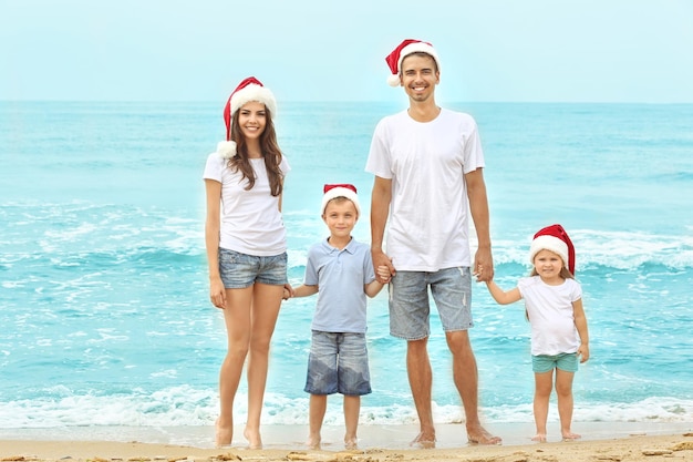 Junges Paar mit Kindern am Strand. Weihnachtskonzept