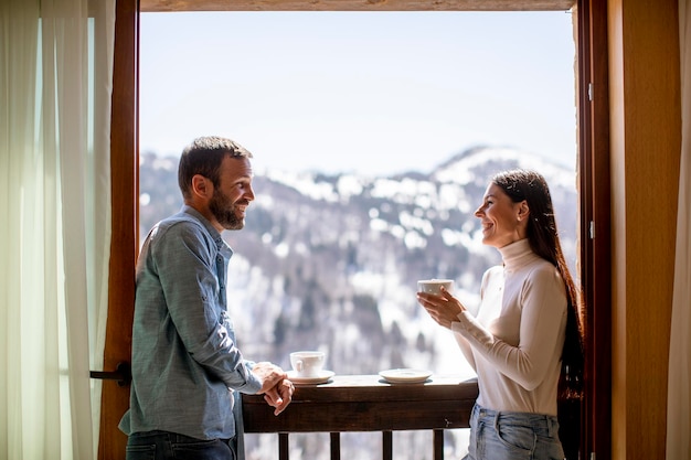 Junges Paar mit Tassen heißem Tee am Winterfenster