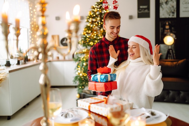 Junges Paar mit Weihnachtsgeschenken zu Hause in der Nähe von Weihnachtsbaum Romantischer Tag Feiertage Silvester