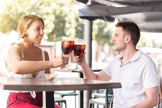 Junges Paar plaudert und stößt mit einem Drink auf einer Außenterrasse an