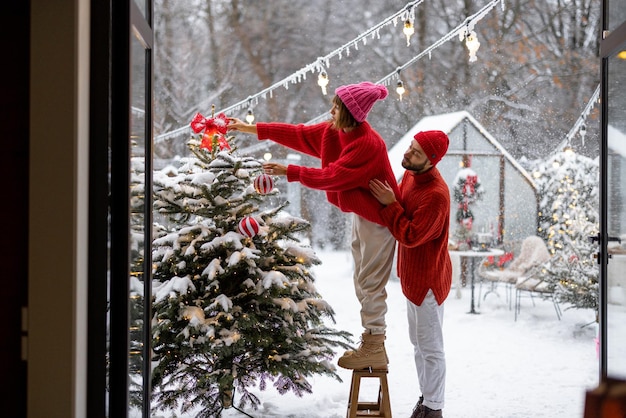 Junges Paar schmückt Weihnachtsbaum im Hinterhof