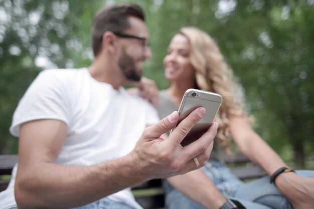 Junges Paar sitzt auf einer Bank und benutzt Smartphone