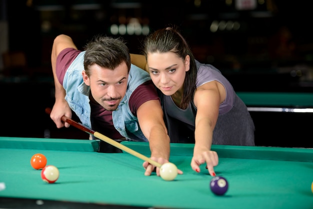 Junges Paar spielt Billard im dunklen Billardclub