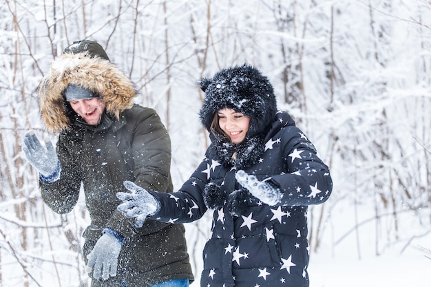 Junges Paar spielt mit Schnee im Winterpark.