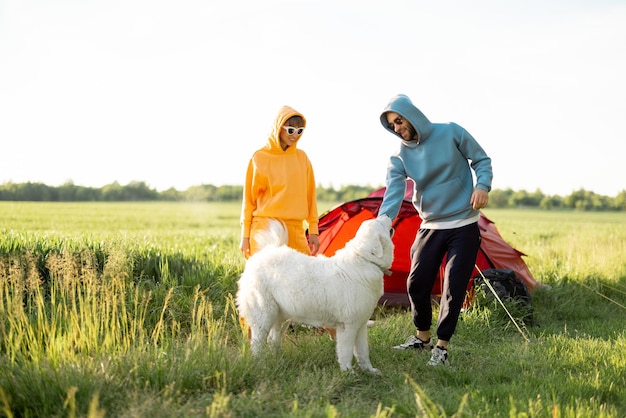 Junges Paar spielt mit seinem Hund auf dem Campingplatz