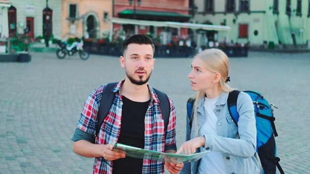 Junges Paar Touristen mit Karte, die nach einem neuen historischen Ort im Stadtzentrum suchen, gehen sie spazieren und f...