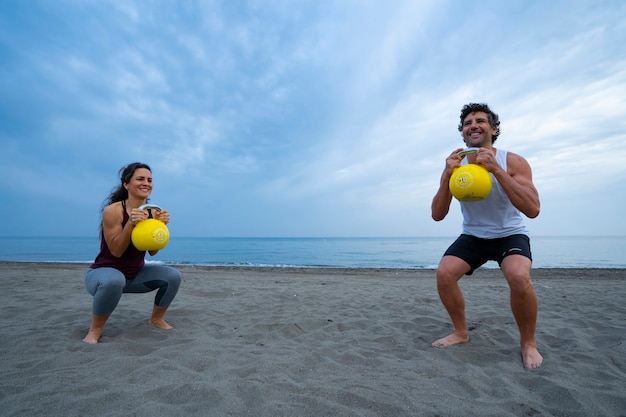 junges Paar trainiert am Strand mit Kesselglocken