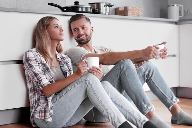 Junges Paar trinkt Kaffee auf dem Küchenboden