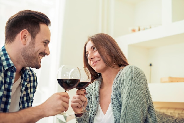 Junges Paar trinkt Rotwein und lächelt