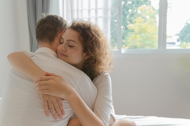 Junges Paar umarmt sich glücklich im Bett