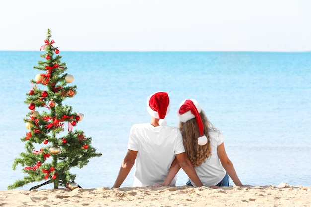 Junges Paar und Weihnachtsbaum am Strand