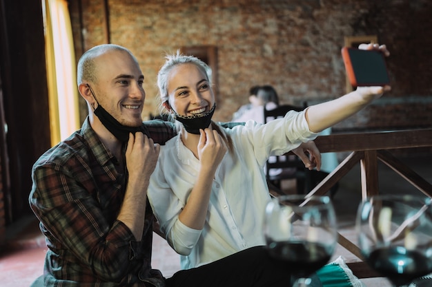 Junges Paar verliebt in offene Gesichtsmasken, die Selfie in einem Restaurant nehmen