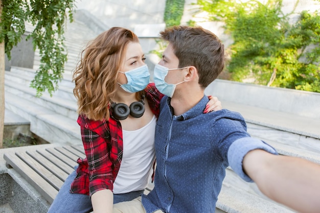 Junges Paar verliebt, Mann und Frau küssen sich in medizinischer Schutzmaske im Gesicht. Konzept der Umweltverschmutzung. Pandemie Coronavirus (Covid-19), Virenschutz